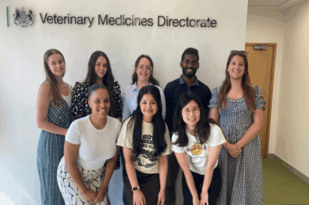 The photo is of a group of eight veterinary students. They are standing in front of a sign that says Veterinary Medicines Directorate.